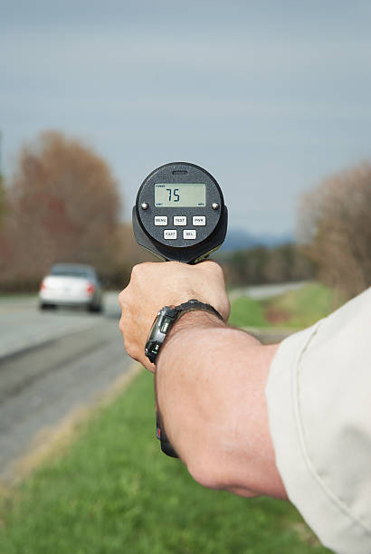 Police officer holding a speed radar. Car speeding at 75 mph.