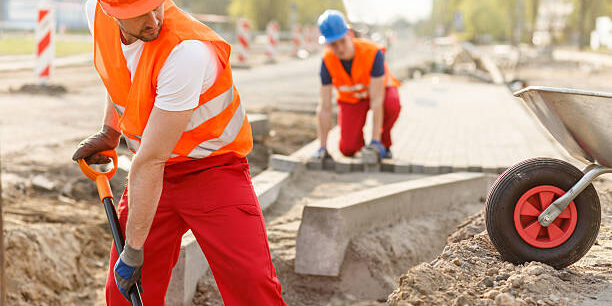 Two hard working builders in uniforms putting pavement